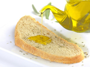 pouring virgin olive oil on a slice of bread with oregano